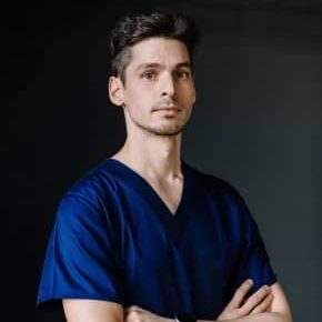 Porträt von Dr. Zsolt Perényi, Implantologe und Leiter Prothetik bei CompletDent Budapest — Mann im dunkelblauen Praxiskleidung mit verschränkten Armen